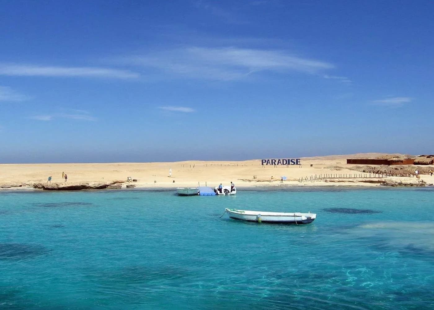 Paradise Island beach sign with rows of small boats along the shoreline