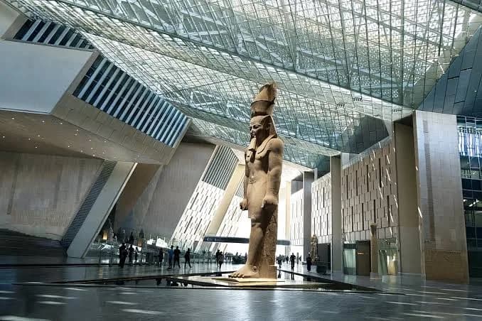 Statue of Ramesses II beneath the Grand Egyptian Museum's dramatic glass ceiling