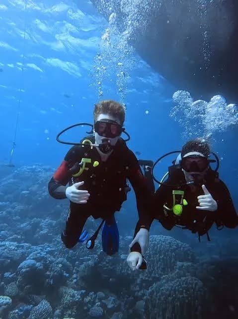 Two divers giving a thumbs up underwater beneath the boat during an intro dive in Hurghada