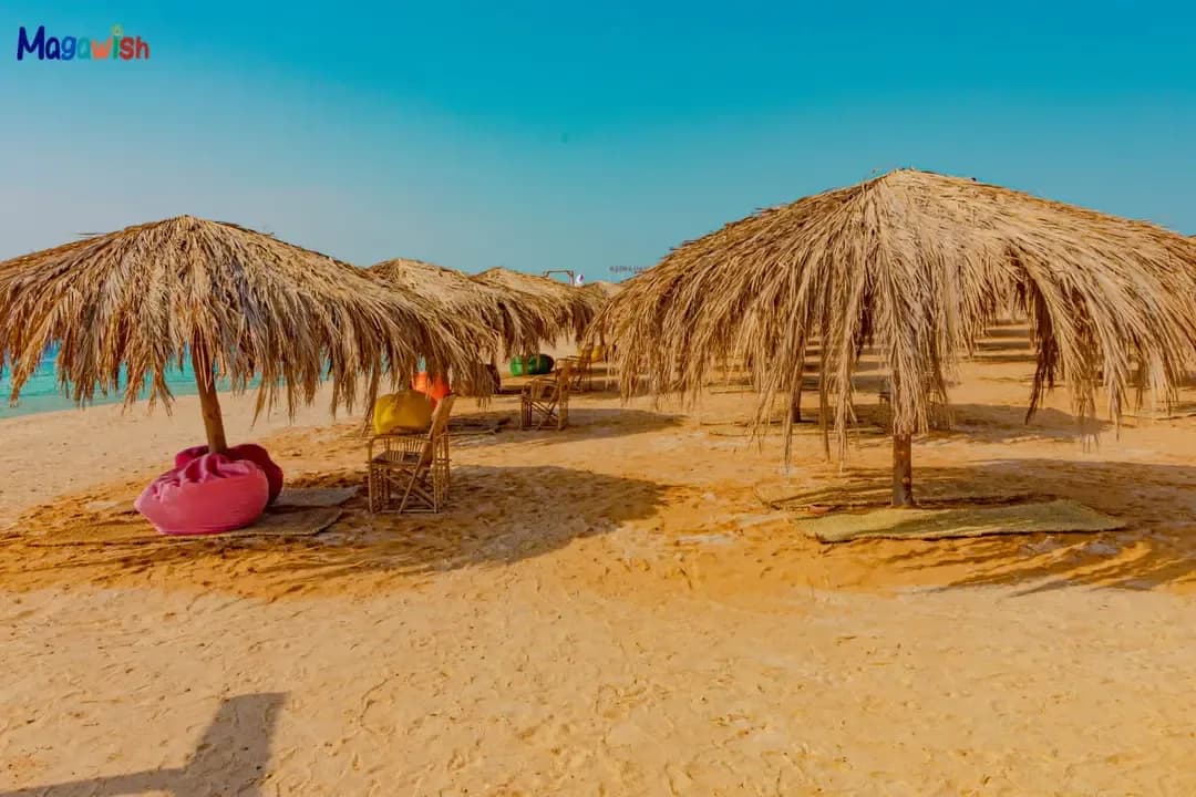 Thatched-roof sunshade loungers on the beach at Magawish Island